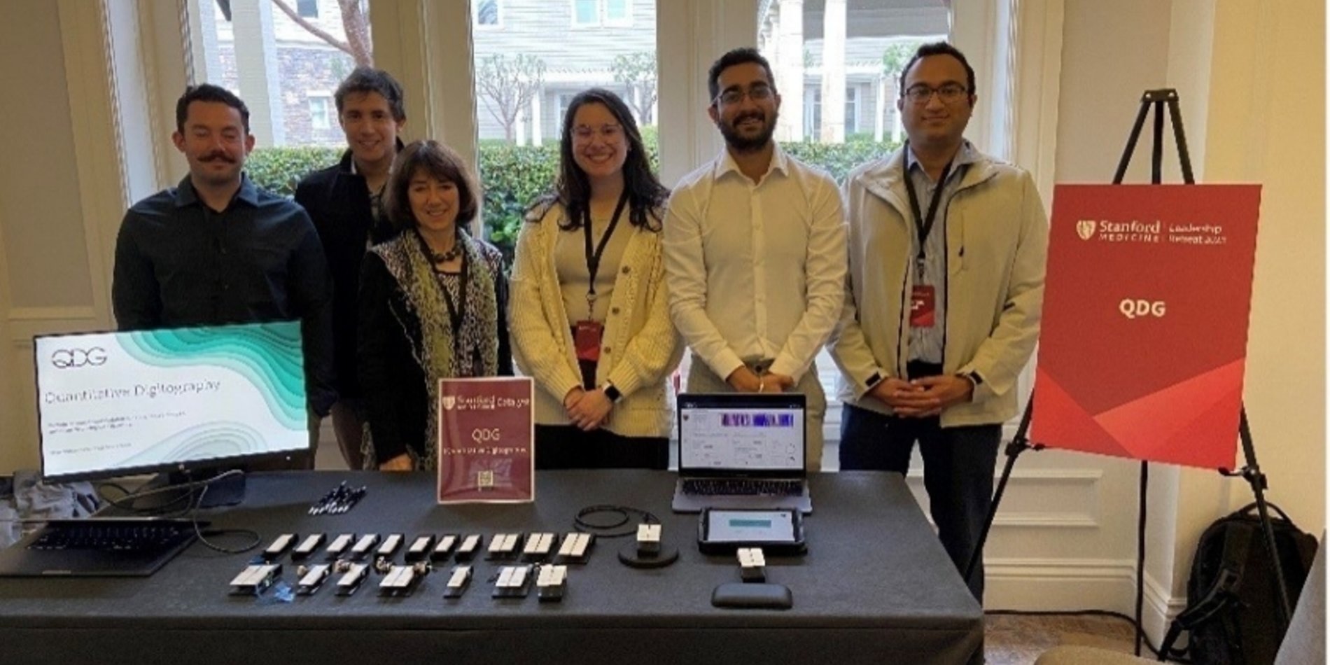 The QDG project team presenting finger-tapping devices and a monitoring dashboard.